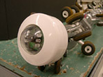 Head of robot: a white toroid-like shape with a clear dome in the center, and the video camera peeking out from the inside